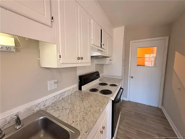 a kitchen with granite countertop a sink a stove and cabinets