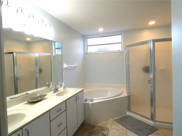 a bathroom with a bathtub shower sink vanity and mirror
