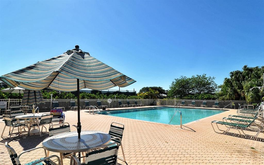 8901 Veranda Way, Unit 111 Sarasota, FL 34238 - Photo 38 of 41 a view of a swimming pool with a table and chairs under an umbrella