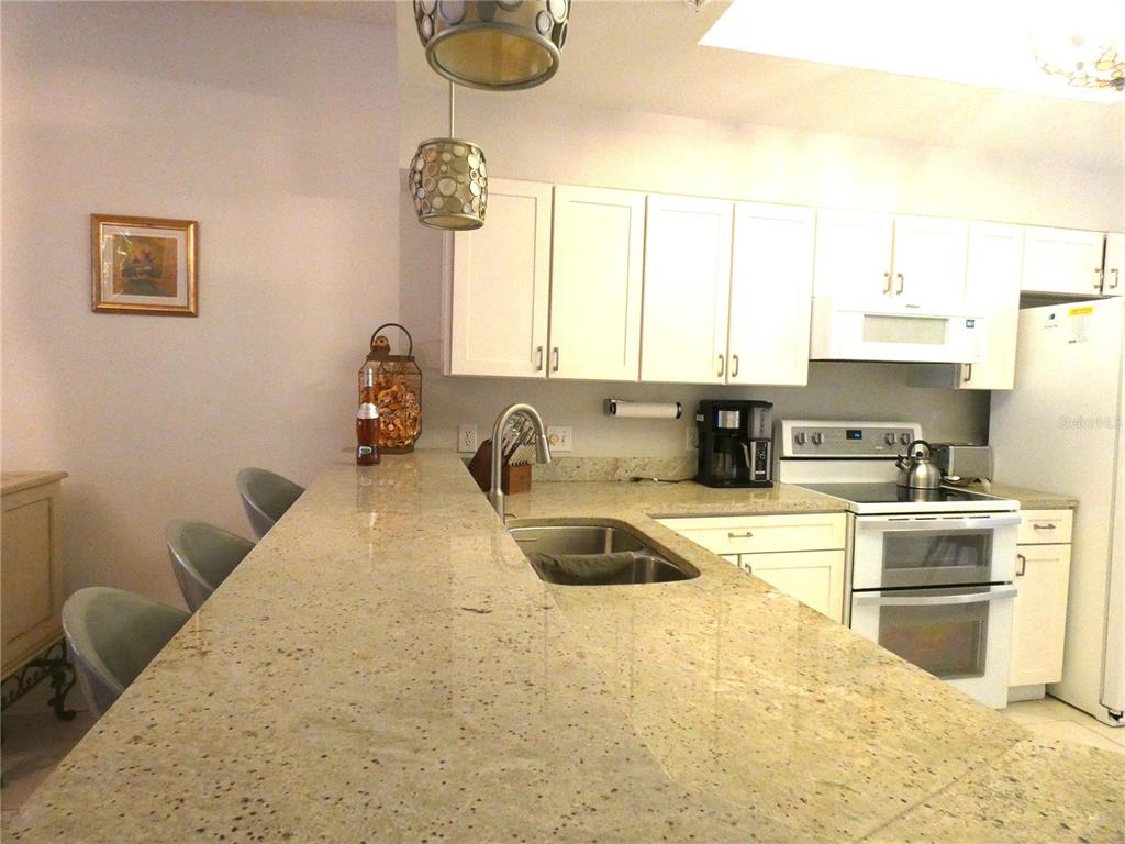 8901 Veranda Way, Unit 111 Sarasota, FL 34238 - Photo 6 of 41 a kitchen with a stove a sink and a refrigerator