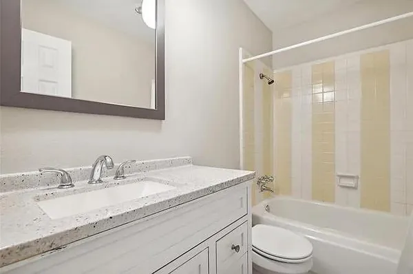 a bathroom with a granite countertop sink a toilet and a bathtub