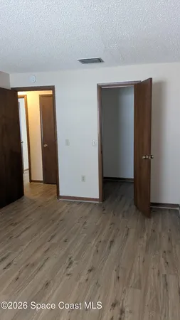 a view of an empty room with wooden floor and closet