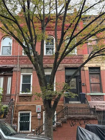 a front view of a house with a tree