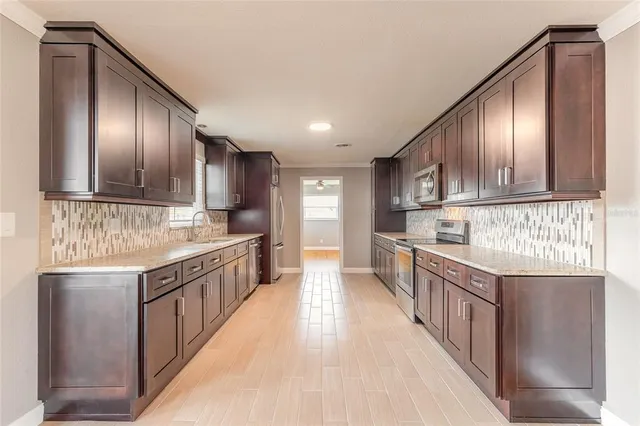 a kitchen with stainless steel appliances granite countertop wooden cabinets a sink and dishwasher a oven with wooden cabinets