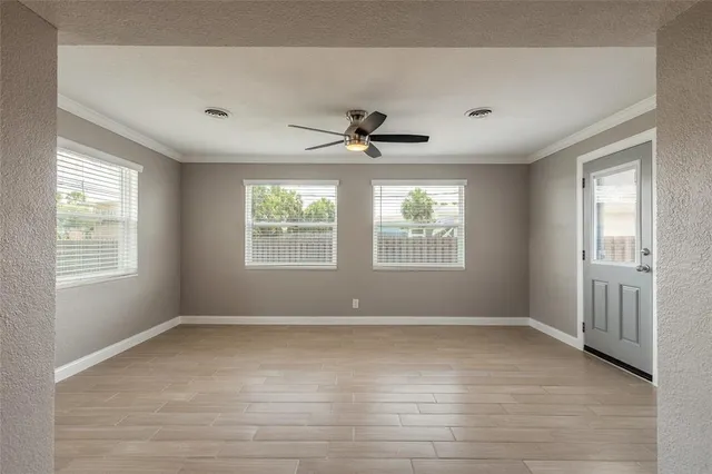 a view of an empty room with wooden floor and a window