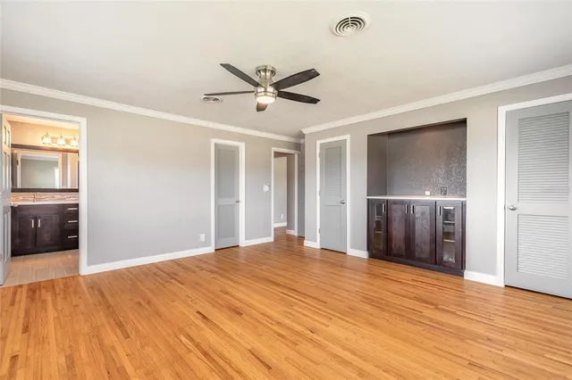 a view of empty room with wooden floor and ceiling fan