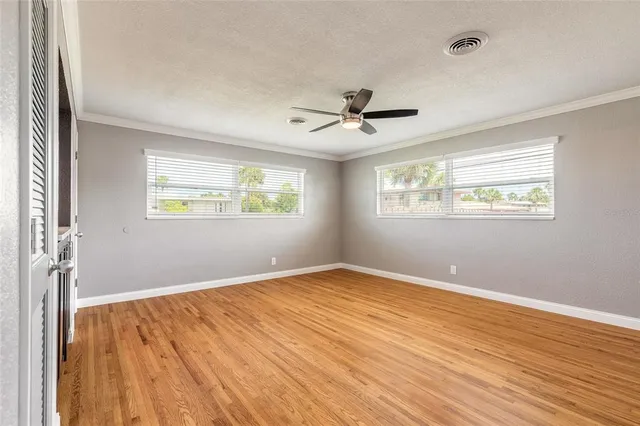 a view of an empty room with a window and wooden floor