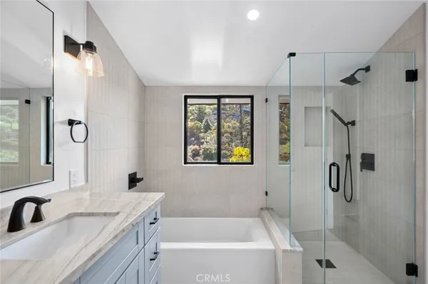 a bathroom with a tub sink vanity granite and shower