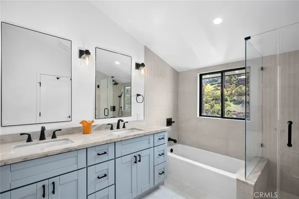 a bathroom with a granite countertop sink mirror double vanity tub and shower