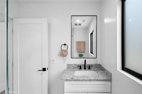a bathroom with a granite countertop sink and a mirror