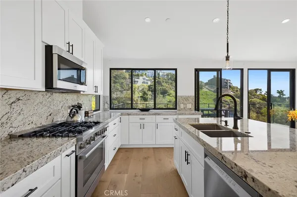 a kitchen with stainless steel appliances granite countertop a stove a sink and a microwave