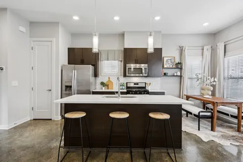 a kitchen with stainless steel appliances kitchen island granite countertop a sink stove and refrigerator