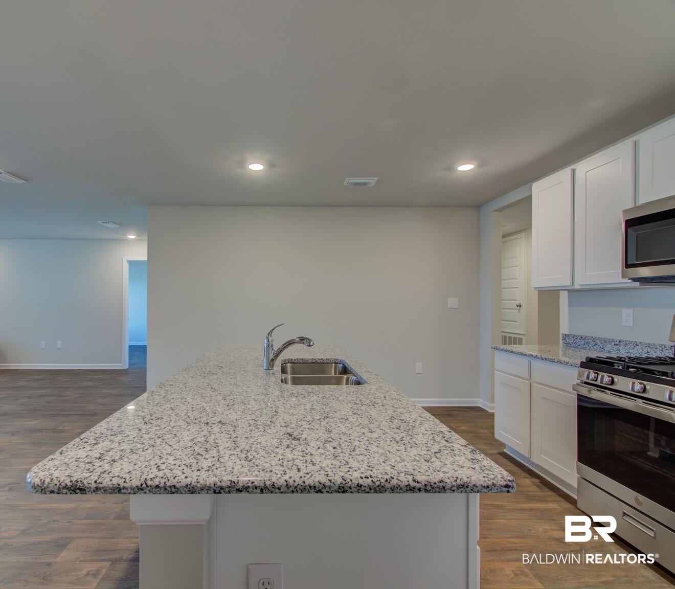 23952 Citation Loop Daphne, AL 36526 - Photo 17 of 69 Kitchen featuring dark wood-style flooring, stainless steel appliances, light stone counters, white cabinetry, and a center island with sink