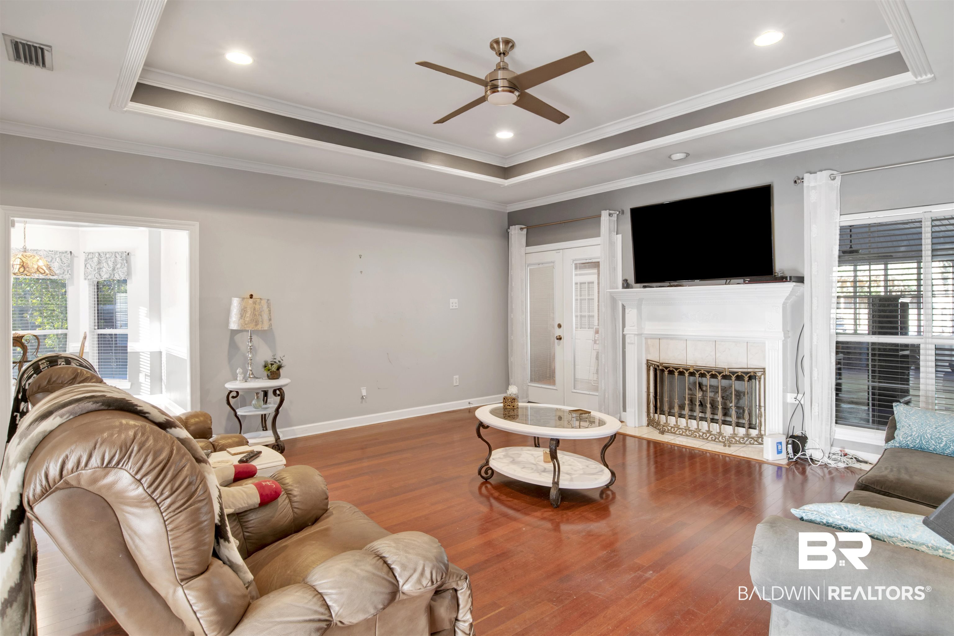 445 Wedgefield Drive South Mobile, AL 36608 - Photo 8 of 36 Living room featuring a tray ceiling, a fireplace, a healthy amount of sunlight, and wood-type flooring