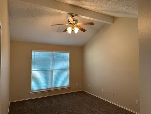 an empty room with a window and a ceiling fan