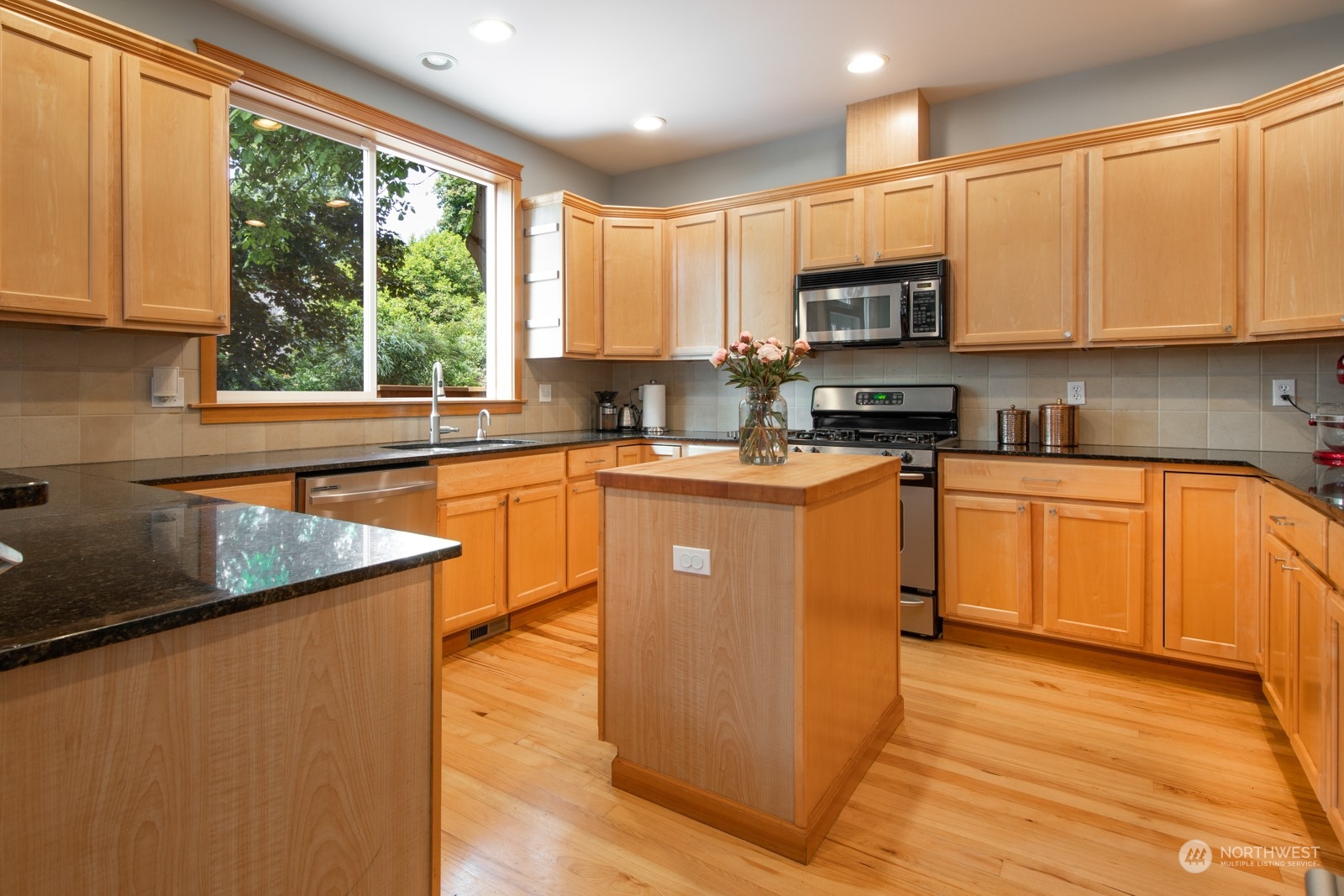 319 18th Avenue Seattle, WA 98122 - Photo 7 of 38 a kitchen with stainless steel appliances granite countertop wooden cabinets a sink a stove a refrigerator with grey cabinets and wooden floor
