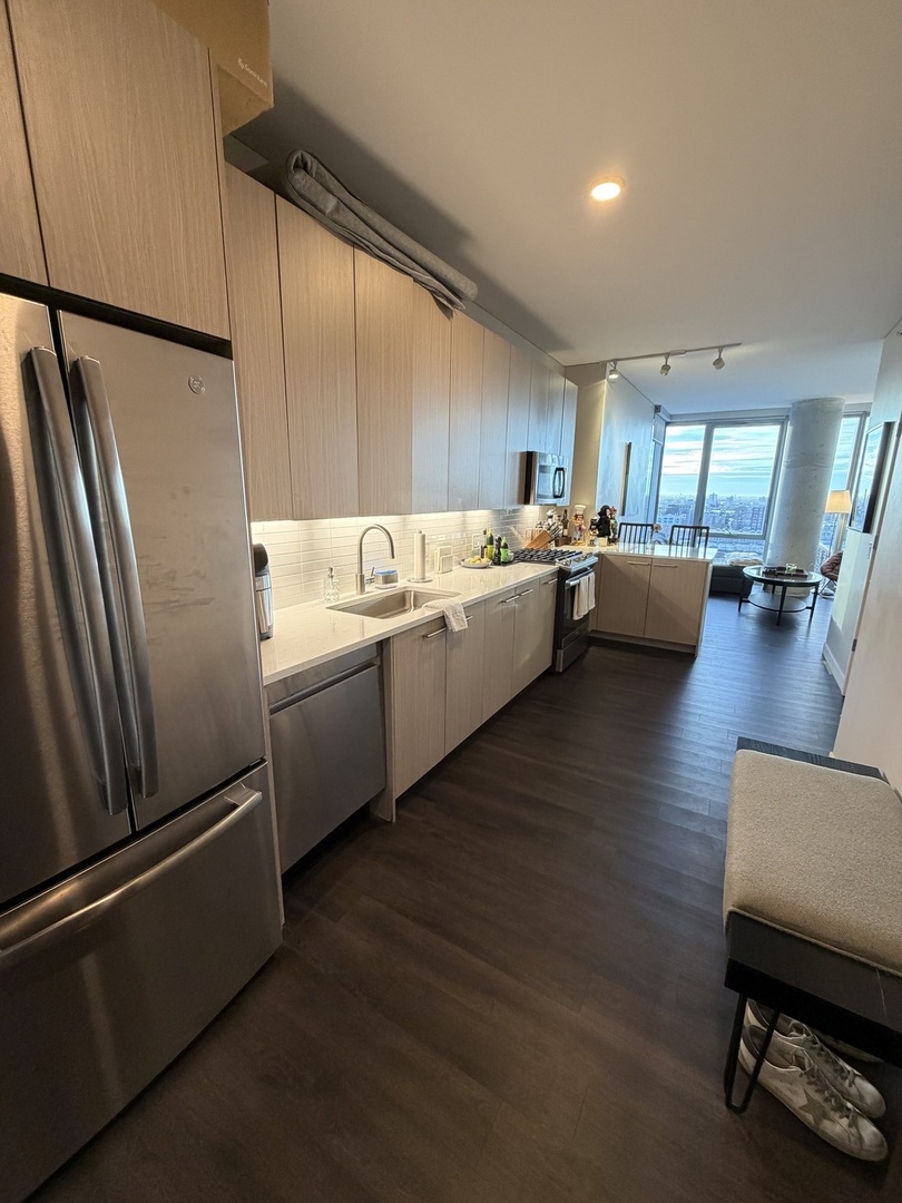 205 South Peoria Street, Unit 1515 Chicago, IL 60607 - Photo 13 of 17 a kitchen with stainless steel appliances wooden floor and a refrigerator