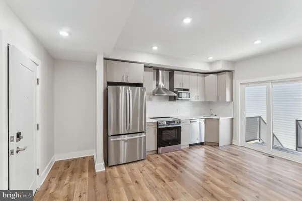 a kitchen with granite countertop a refrigerator and a stove top oven