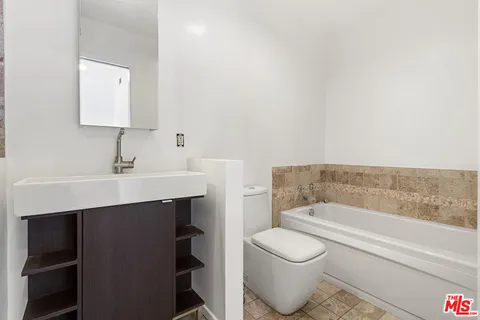 a bathroom with a sink toilet a mirror and bathtub