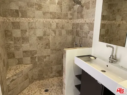 a bathroom with a sink shower and a mirror
