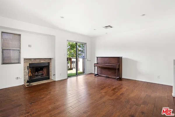 a view of an empty room with wooden floor fireplace and a window