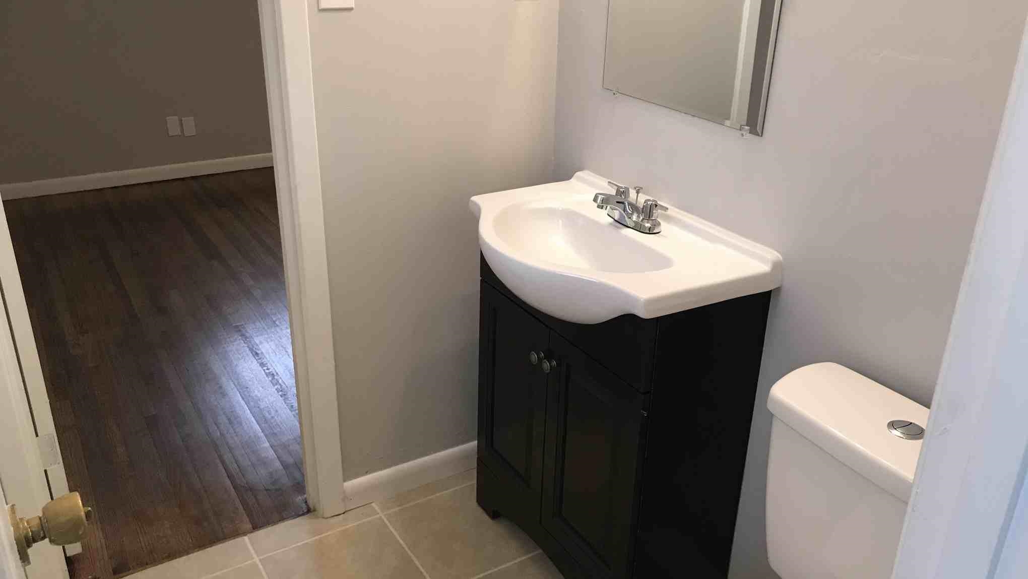 4502 Cottonwood Road Memphis, TN 38118 - Photo 14 of 16 Bathroom featuring a dark wood-finish vanity with an integrated white sink, chrome faucet, and a toilet