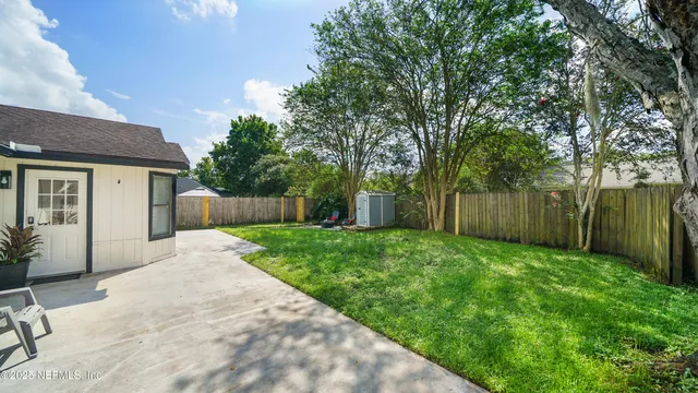 a view of a backyard with large trees and wooden fence