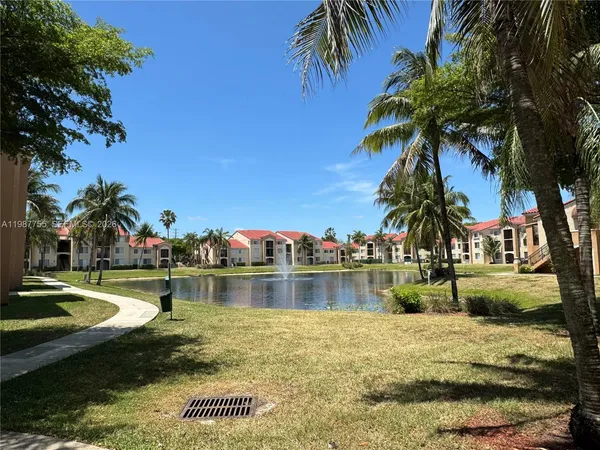 a view of swimming pool with a yard and palm trees