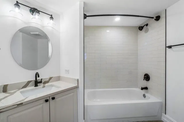 a bathroom with a granite countertop sink a mirror and a bathtub