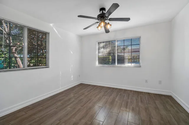 a view of empty room with wooden floor and fan