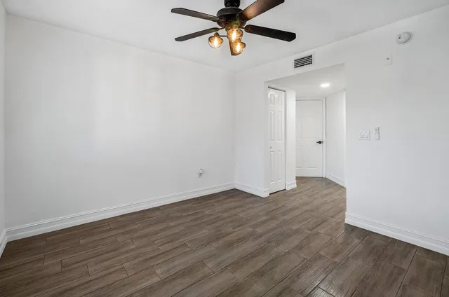 a view of an empty room with window and wooden floor