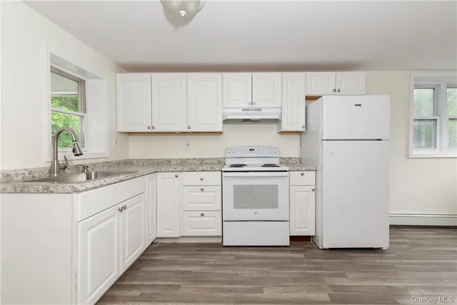a kitchen with granite countertop white cabinets and white appliances