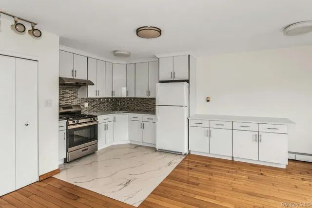 a kitchen with granite countertop a stove cabinets and wooden floor