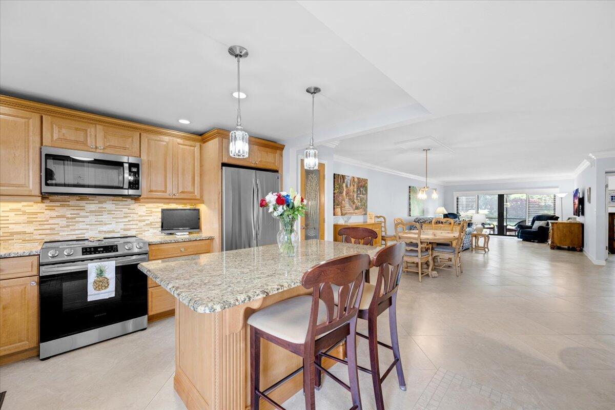 a kitchen with stainless steel appliances granite countertop a stove top oven a sink a dining table and chairs with the wooden floor