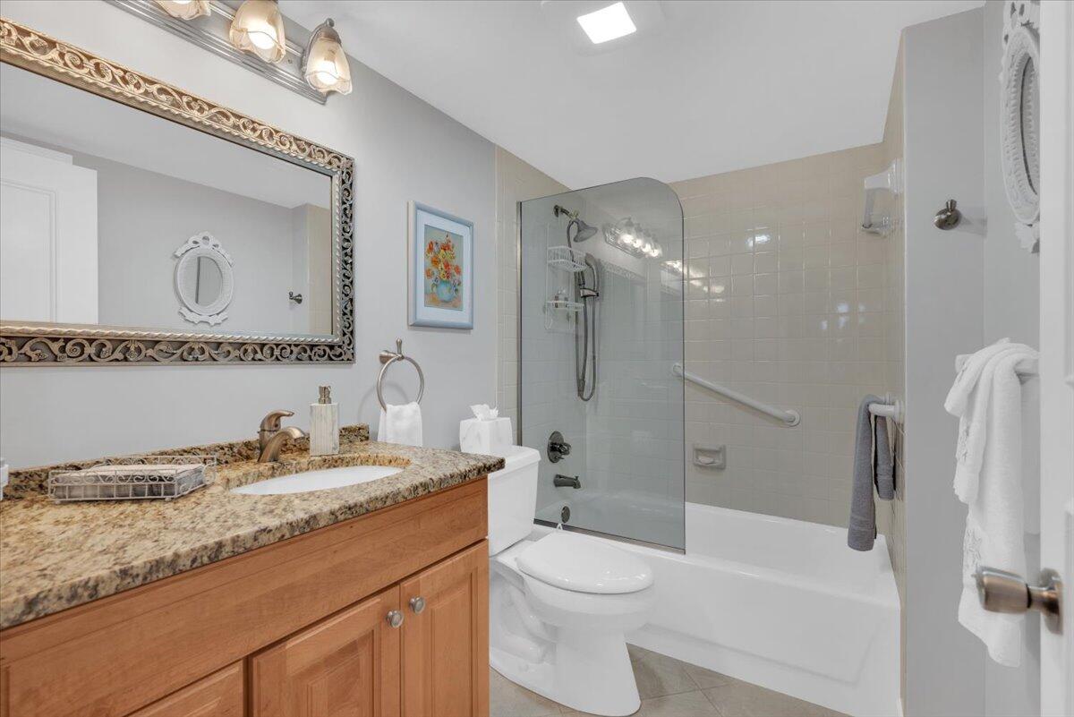 300 North Hwy A1A, Unit 104O Jupiter, FL 33477 - Photo 12 of 25 a bathroom with a granite countertop sink mirror vanity and toilet