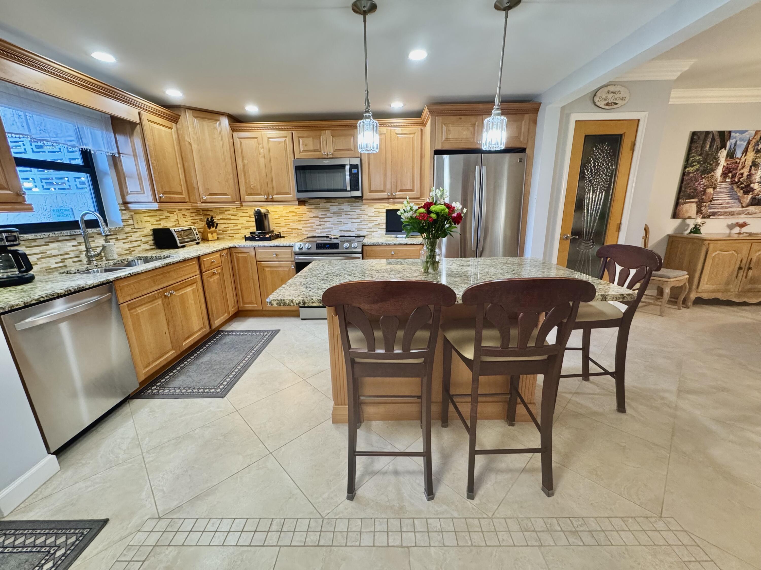 300 North Hwy A1A, Unit 104O Jupiter, FL 33477 - Photo 5 of 25 a kitchen with stainless steel appliances granite countertop a stove a sink a microwave a refrigerator with a dining table and chairs