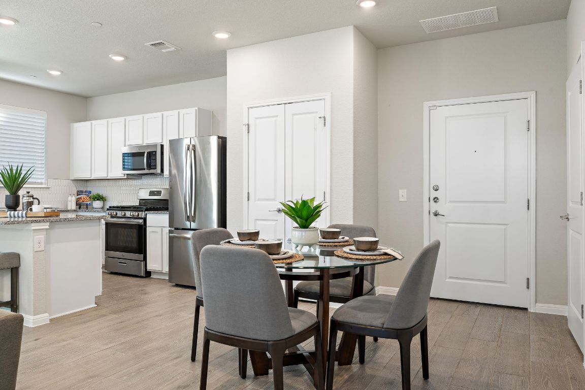 a view of kitchen with refrigerator stove dining table and chairs