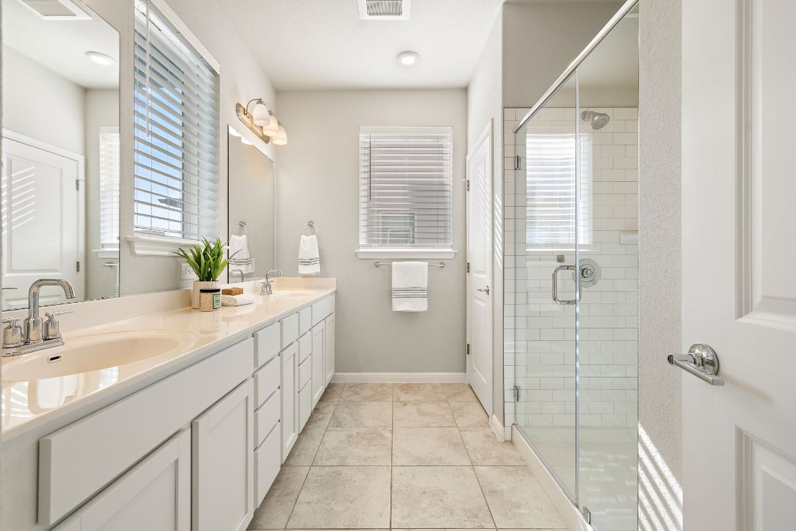 9015 Cattle Baron Path, Unit 504 Austin, TX 78747 - Photo 16 of 36 a spacious bathroom with a double vanity sink a large mirror and shower