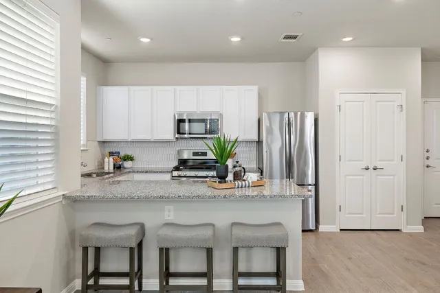 a kitchen with stainless steel appliances granite countertop a table chairs sink refrigerator and microwave