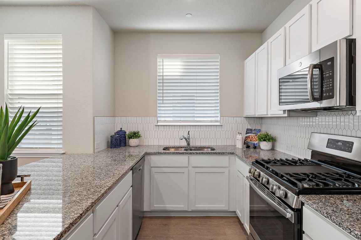 9015 Cattle Baron Path, Unit 504 Austin, TX 78747 - Photo 10 of 36 a kitchen with granite countertop a sink stove and cabinets