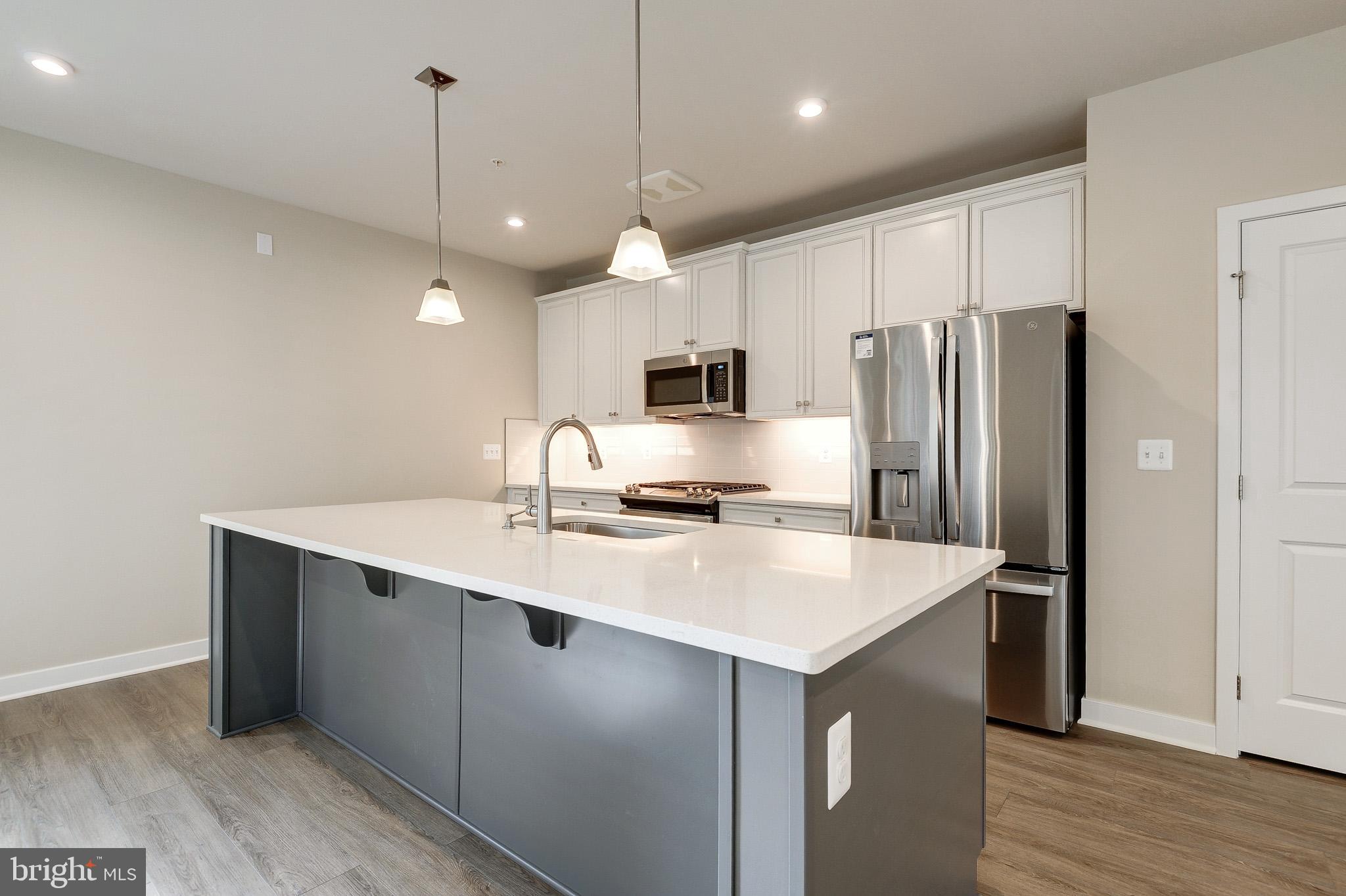 4395 Peach Lily Lane, Unit 304 Chantilly, VA 20151 - Photo 2 of 36 a kitchen with kitchen island a sink stainless steel appliances and wooden floor