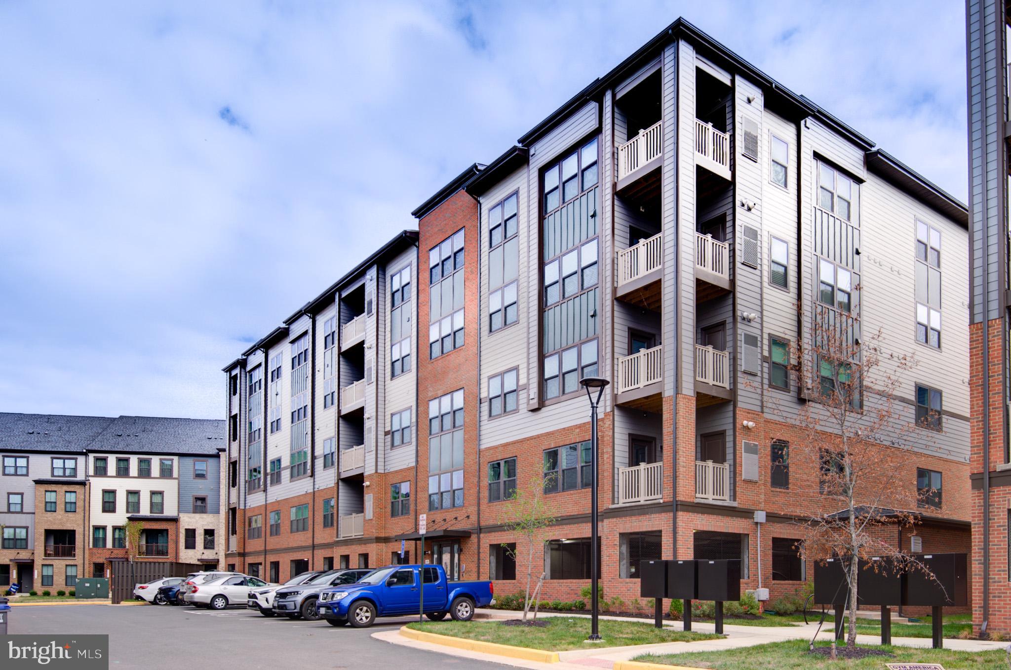4395 Peach Lily Lane, Unit 304 Chantilly, VA 20151 - Photo 34 of 36 a front view of a building with lot of cars and trees