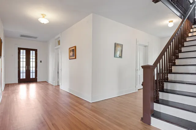 a view of a hallway with wooden floor and stairs