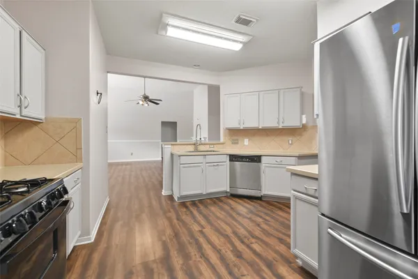 a kitchen with a refrigerator stove and white cabinets with wooden floor