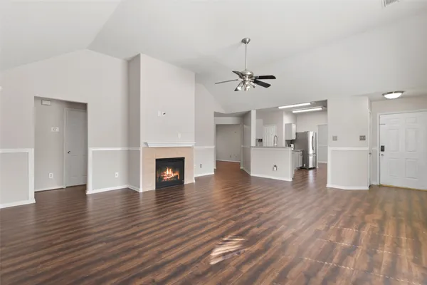 a view of a livingroom with wooden floor and a kitchen