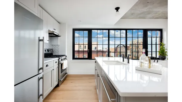 a large white kitchen with kitchen island a large window a sink and stainless steel appliances