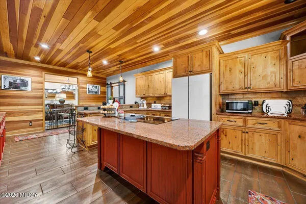 a kitchen with stainless steel appliances granite countertop a refrigerator a sink dishwasher a stove and white countertops with wooden floor