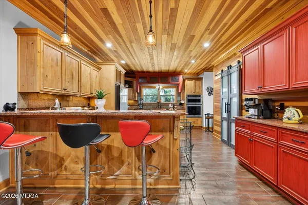 a kitchen with stainless steel appliances granite countertop a kitchen island a stove a sink dishwasher and cabinets with wooden floor