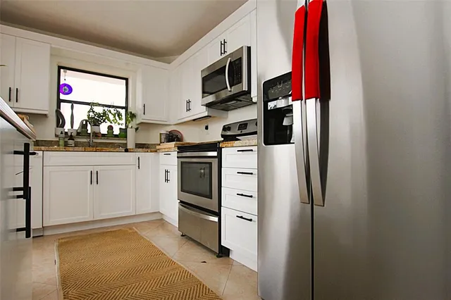 a kitchen with white cabinets and stainless steel appliances