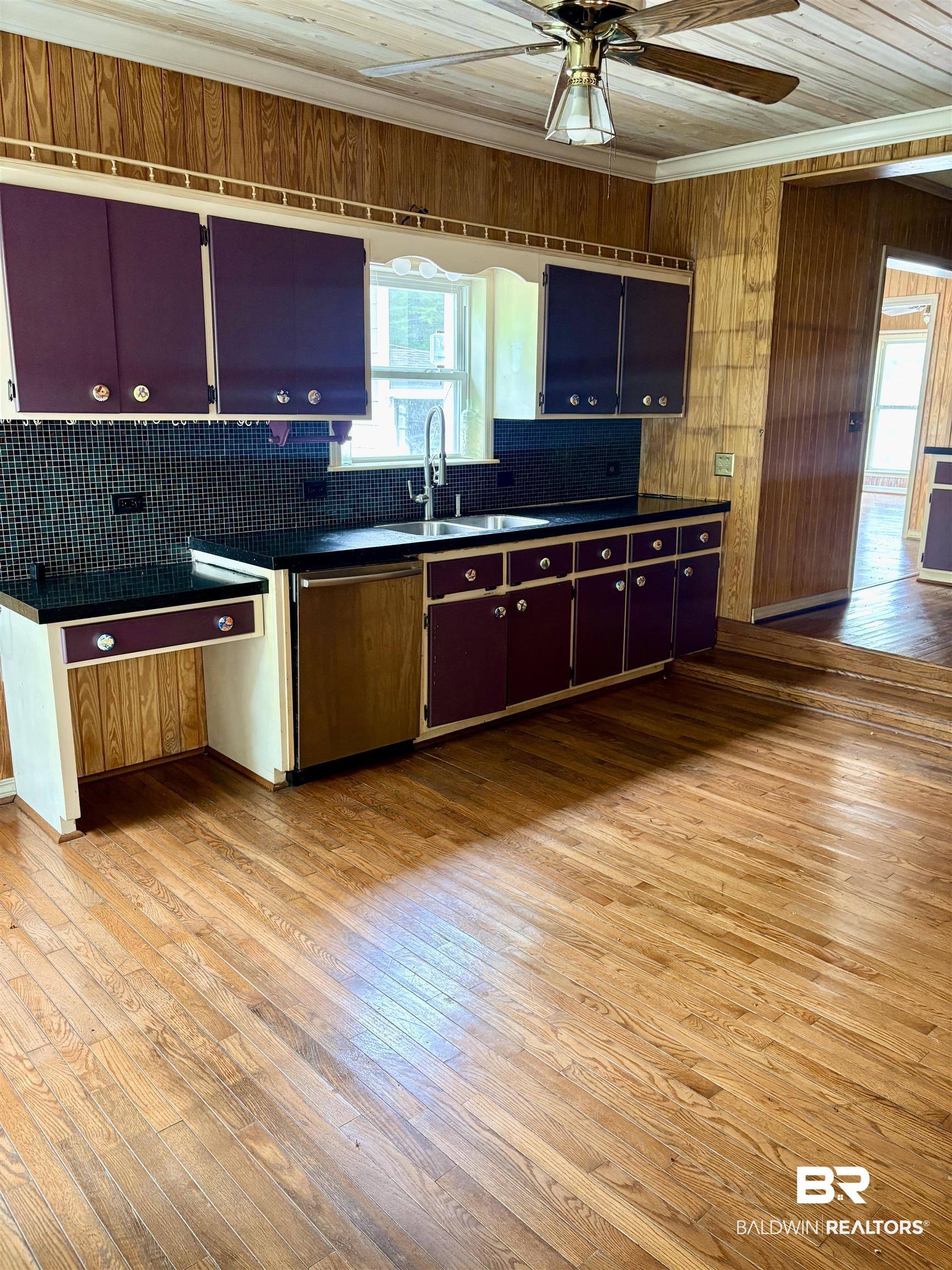 1018 Bates Road Evergreen, AL 36401 - Photo 7 of 21 Kitchen featuring light wood finished floors, dark countertops, ceiling fan, wooden walls, and dishwasher